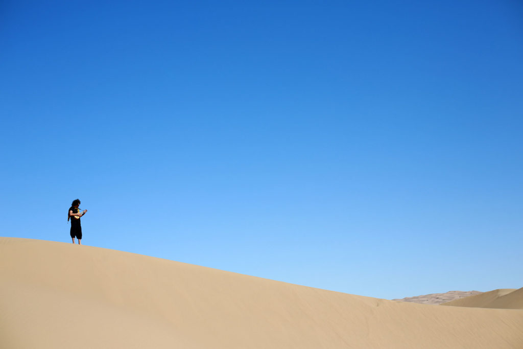 a man standing alone on a big distant dune in Iran