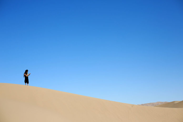 a man standing alone on a big distant dune in Iran