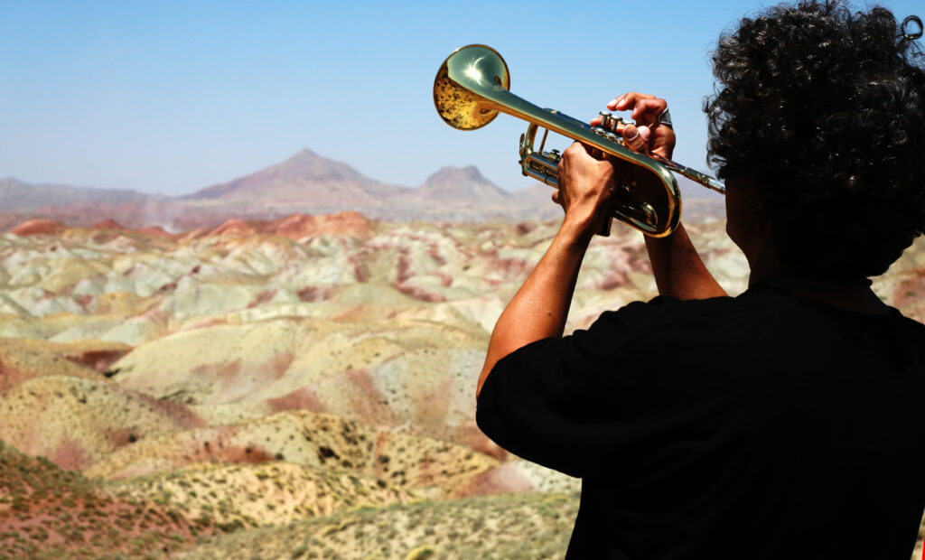 Om Shira playing trumpet on colorful mountains in Iran